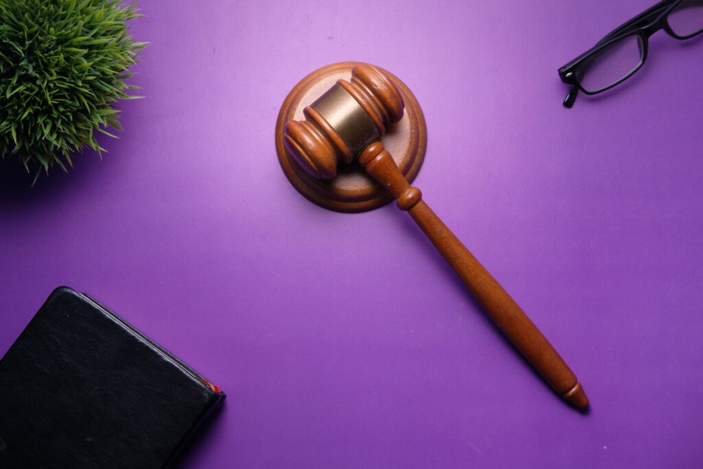 Maillet de juge en bois sur un fond violet, symbolisant la réglementation et la cybersécurité dans le cadre de la directive NIS